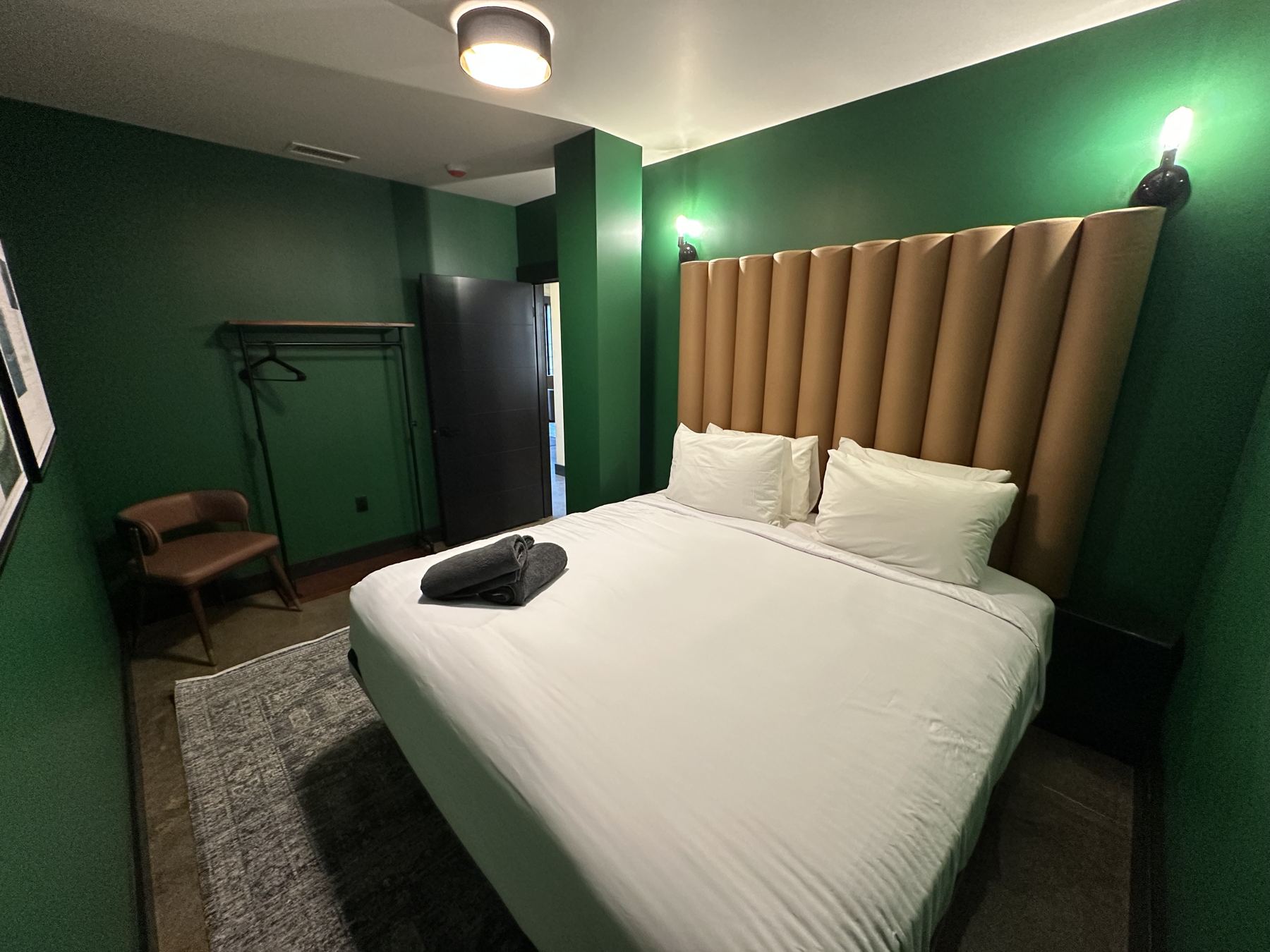 King bedroom with green walls and channel-tufted headboard