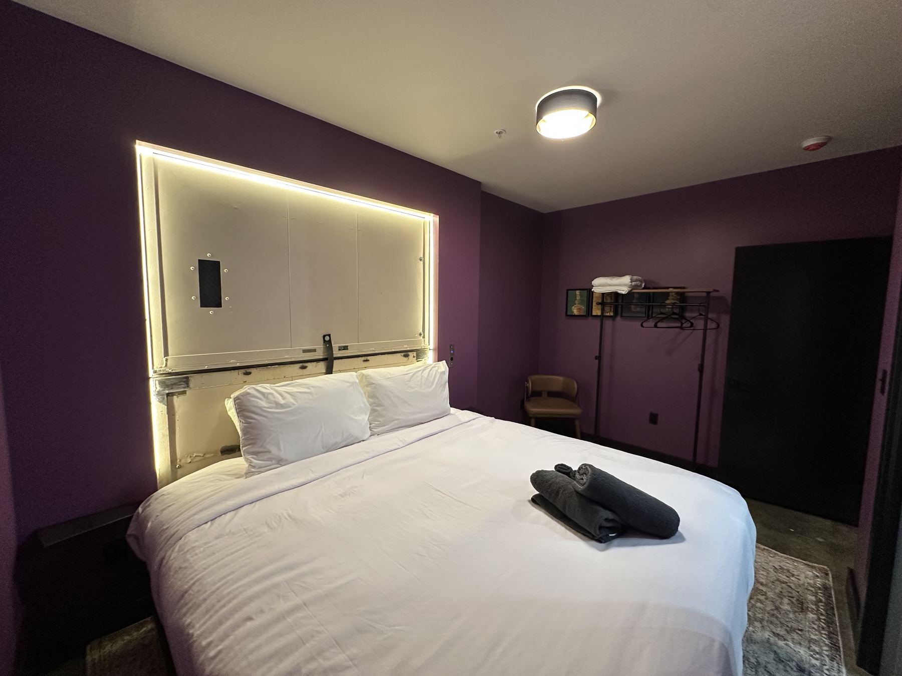 King bedroom with plum walls and backlit headboard